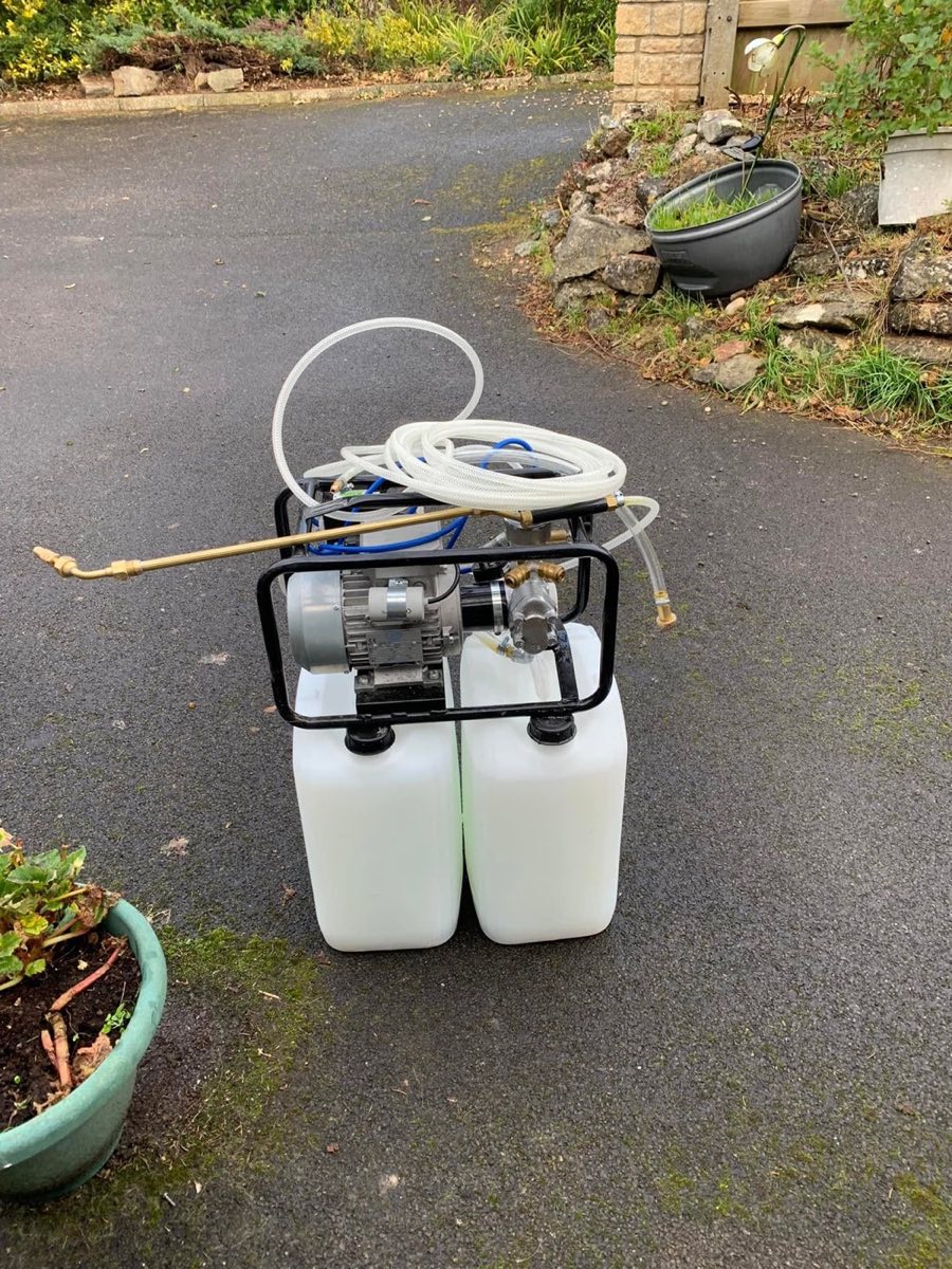 A twin-tank pump unit on a driveway that feeds insecticidal fluid from the tub to a spray lance for woodworm treatment